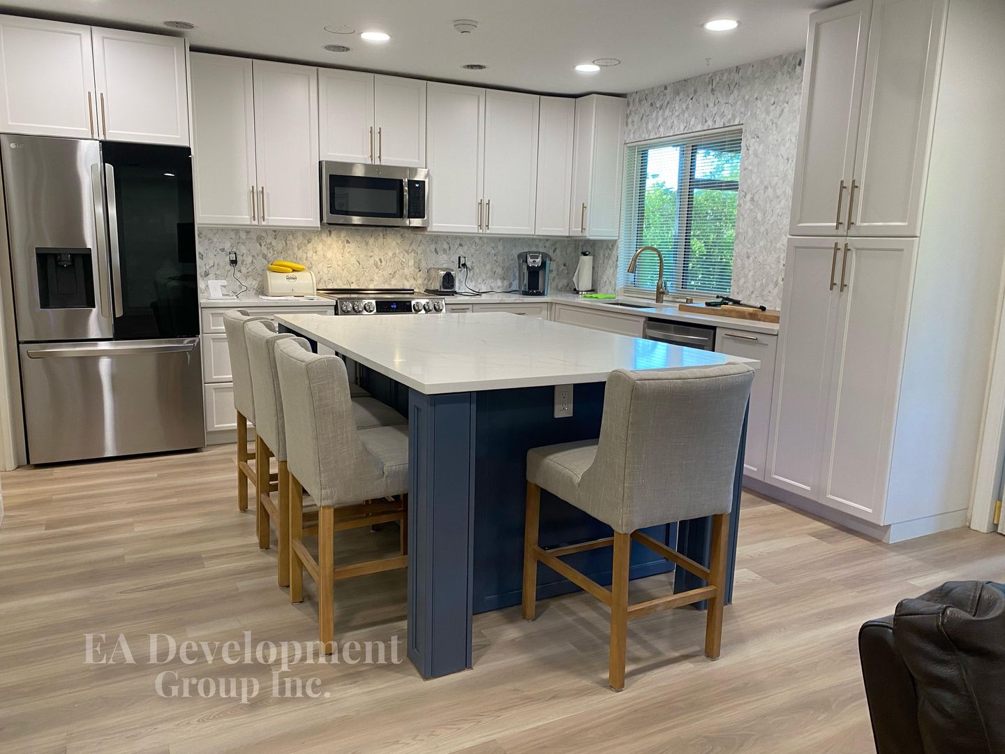 Kitchen renovation after — wide view of white cabinetry and island seating