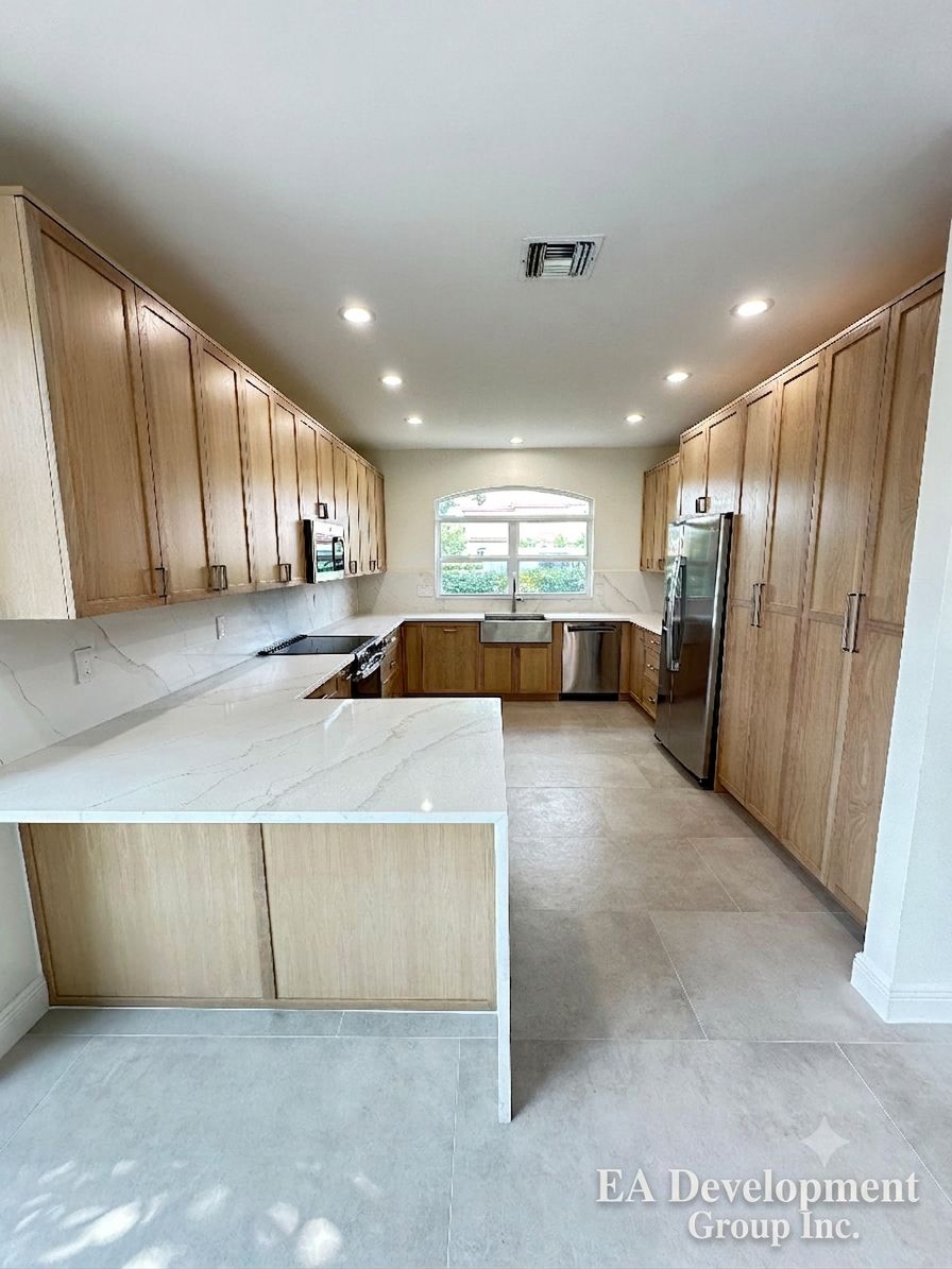 Kitchen renovation after — light oak cabinetry, wide U-shaped view