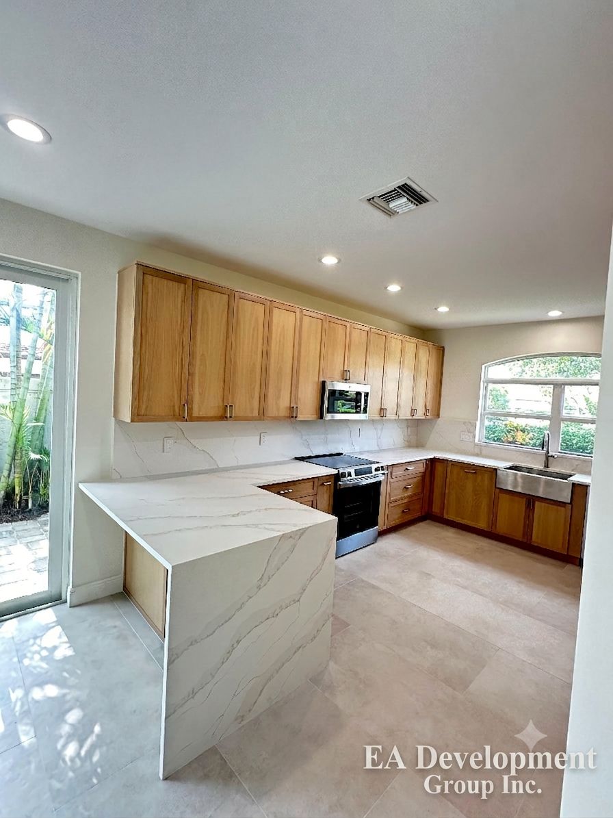 Kitchen renovation after — light oak cabinetry with marble-look backsplash
