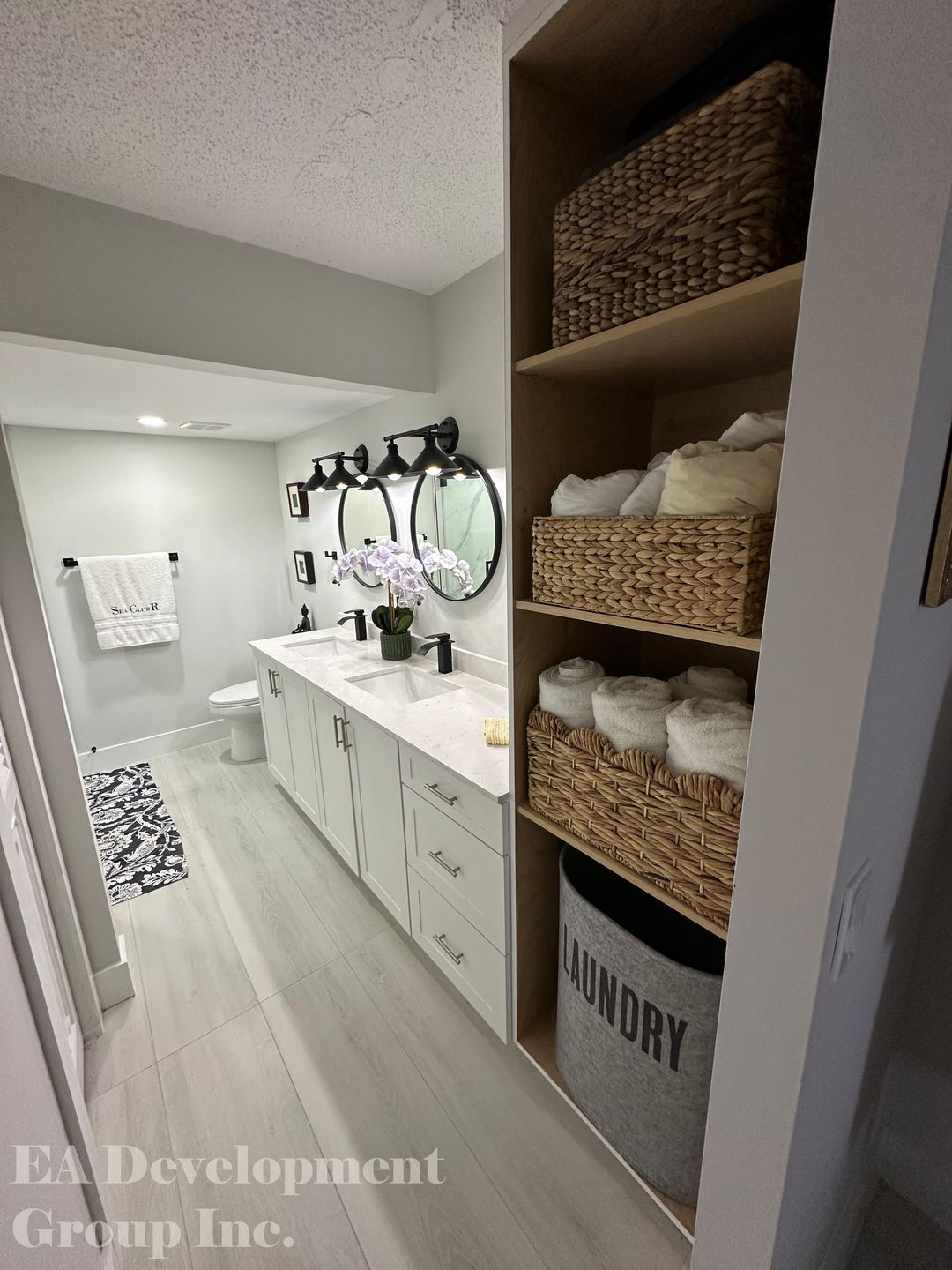 Bathroom renovation after — double vanity with round mirrors and built-in linen shelving