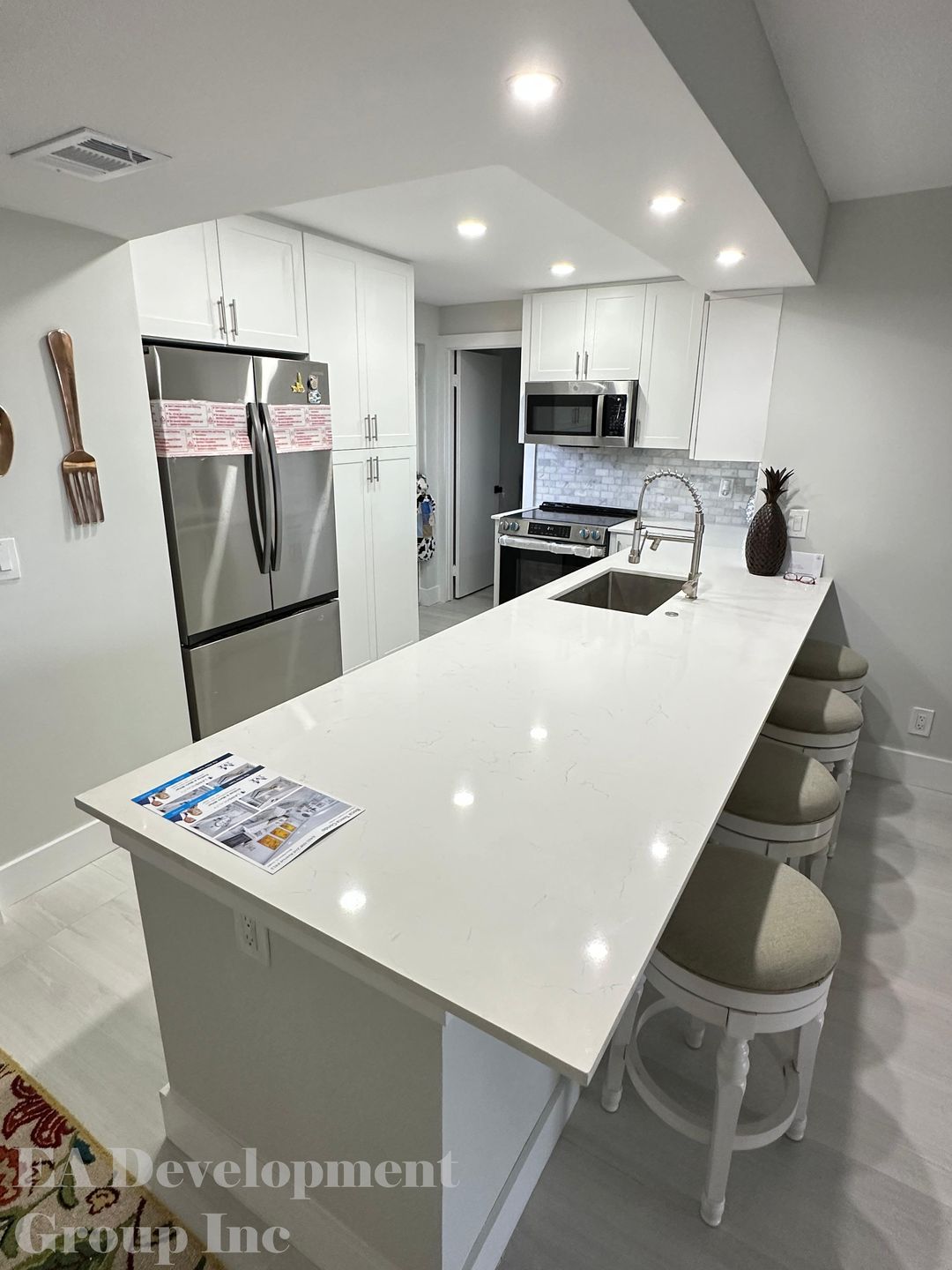 Kitchen renovation after — white cabinetry with quartz island, view 1